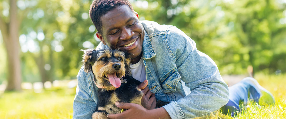 Man relaxing with his dog in the park on a beautiful day.